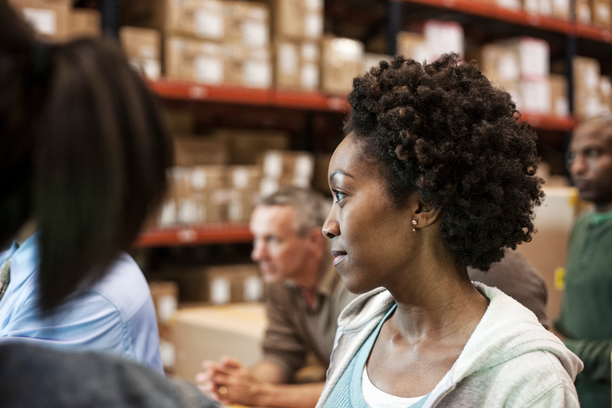 African American female warehouse worker with team of multi-ethnic workers in a large warehouse