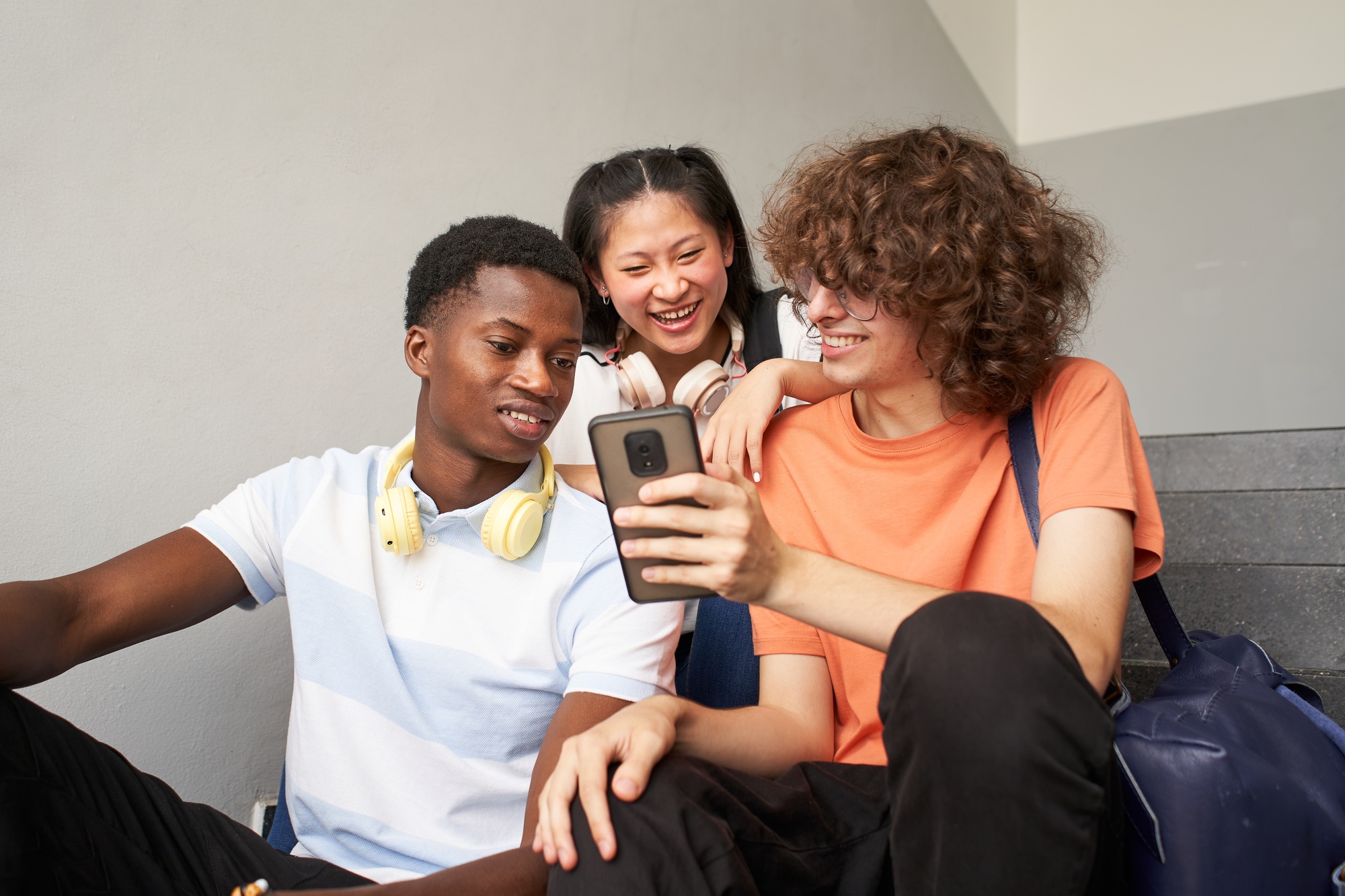 Group of teenage students of different ethnicities sitting on the stairs of the university